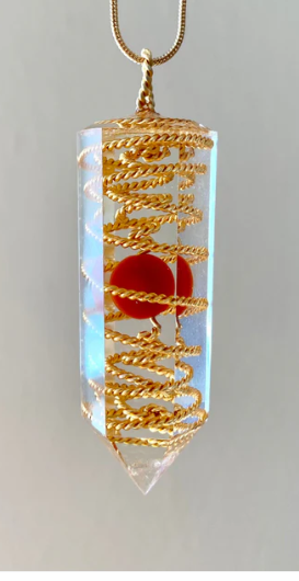 Crystal pendant with gold spiral and red stone on a white background