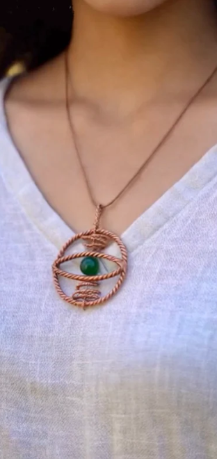 Necklace with a green pendant worn by a person in a white top