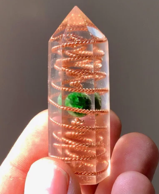 Crystal with spiral design held in a hand against a neutral background