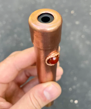 Hand holding a wooden pipe with a dark brown finish against a gray background