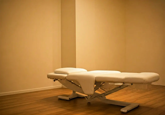 Adjustable med bed in a minimalist wellness clinic with wooden floor and soft lighting