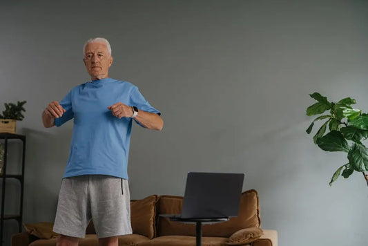 Senior man exercising at home in front of laptop, promoting wellness and healthy aging.