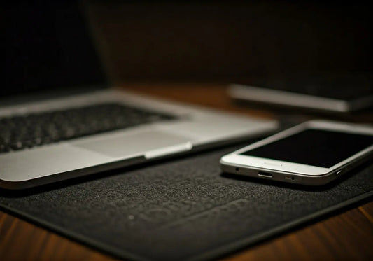 Close-up of a laptop and smartphone on a textured grounding mat for EMF protection