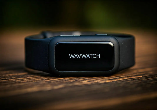 Close-up of a black WAVWATCH wearable wellness device on a wooden surface