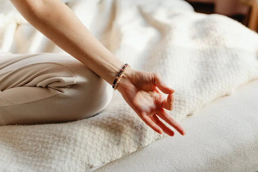 Person meditating in lotus pose on a soft textured bed, wellness and relaxation concept