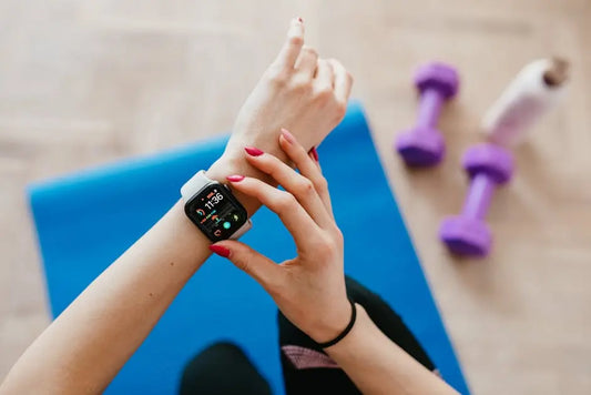 Person using smartwatch on yoga mat with purple dumbbells, fitness and wellness technology