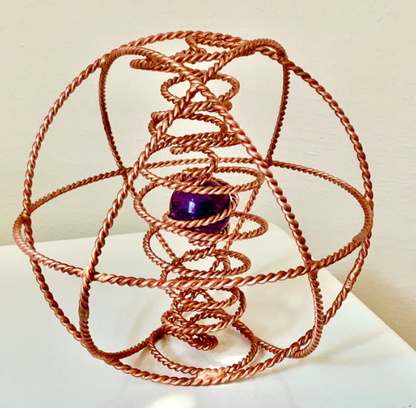 Copper wire sculpture with a purple central object on a white surface