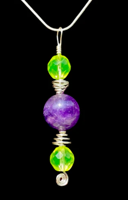 Necklace with green, purple, and yellow beads on a black background