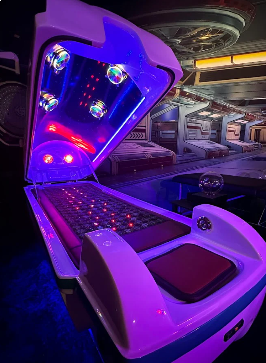 Futuristic Celestial Med Bed Pod with glowing purple accents on a reflective surface