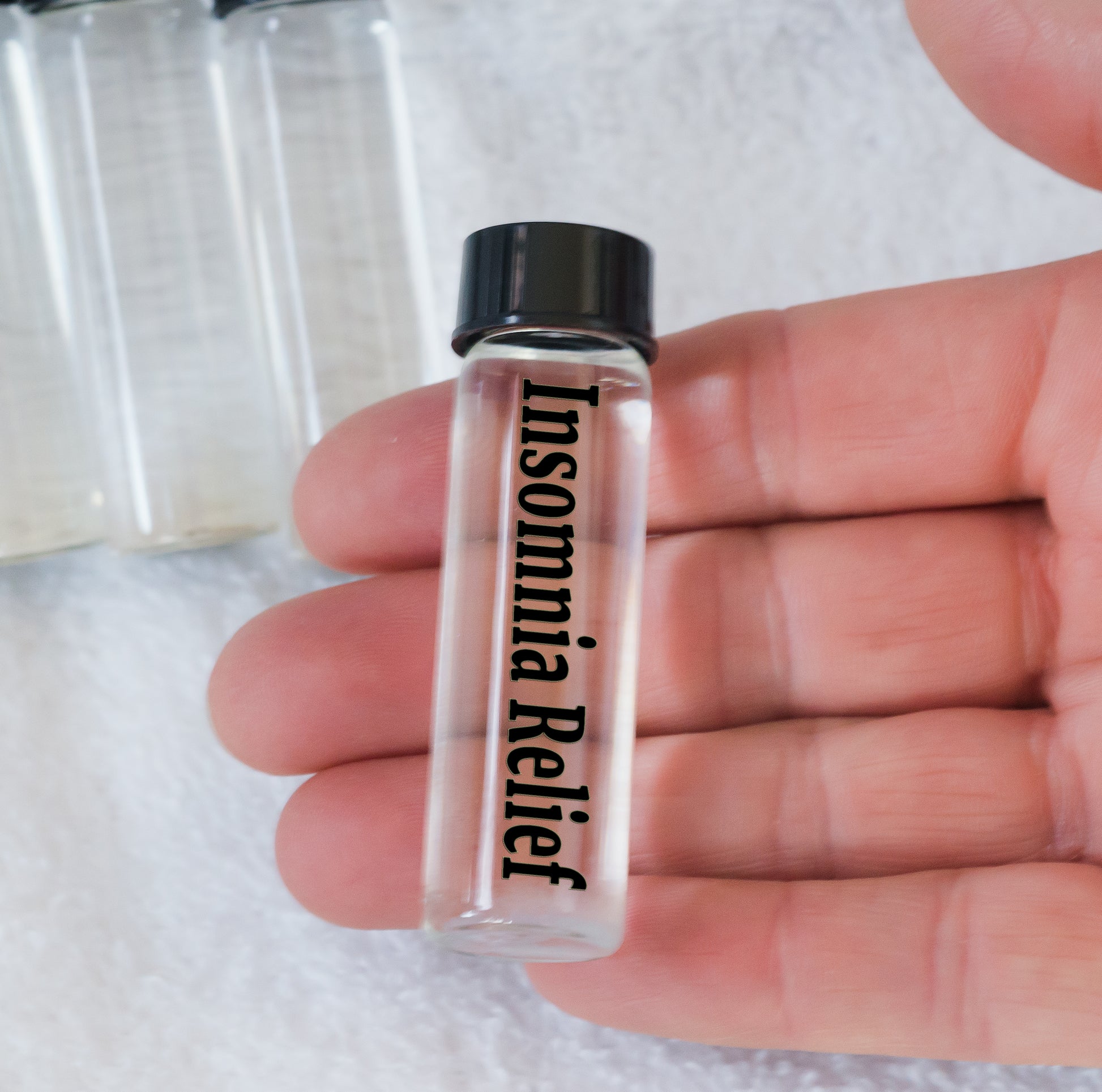 Plasma Energy Water Vial Insomnia Relief A small clear plastic vial with a black cap, labeled 'Insomnia Relief', held in a person's hand.