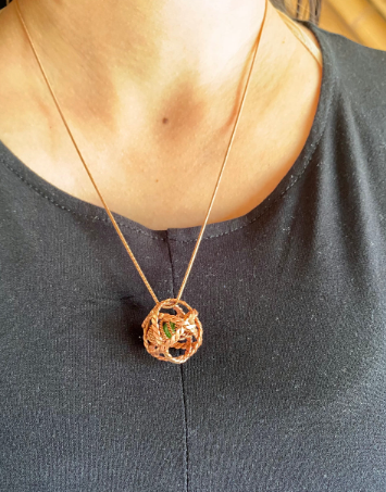Necklace with a spherical pendant on a person wearing a dark top