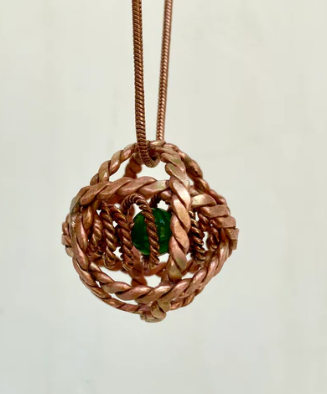 Copper pendant with a green gemstone on a beige background