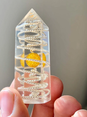 Crystal object with spiral design held in a hand against a neutral background