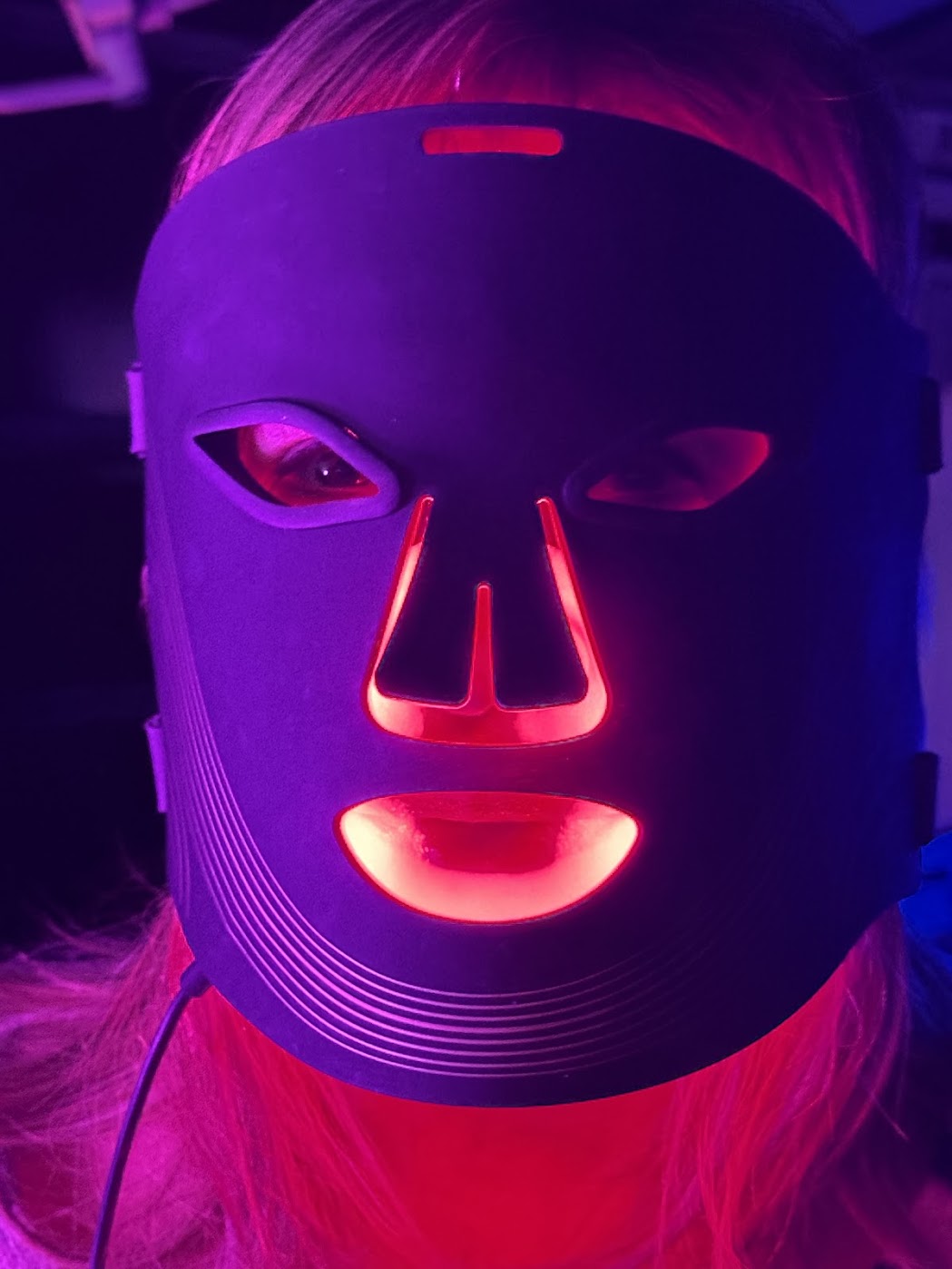 Person wearing a LED face mask with red and purple lights.