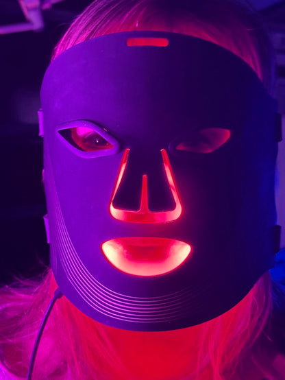 Person wearing a LED face mask with red and purple lights.