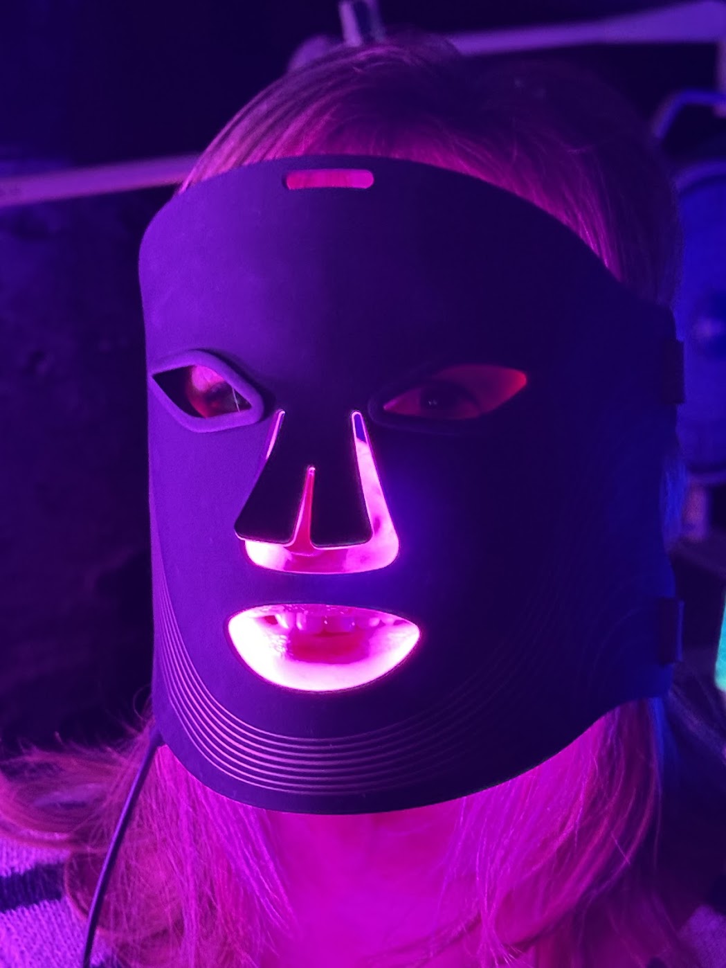 Person wearing a LED red light face mask with purple lighting