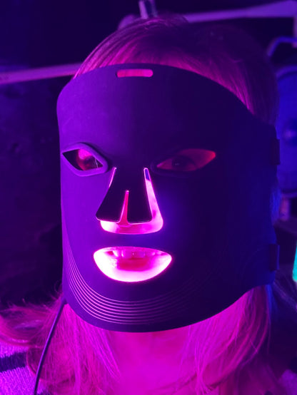 Person wearing a LED red light face mask with purple lighting