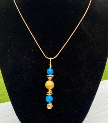 Necklace with blue and yellow beads on a black stand