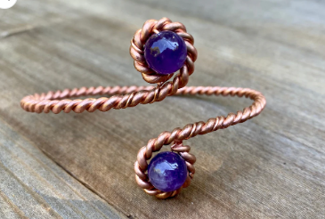 Copper bracelet with purple stones on a wooden surface