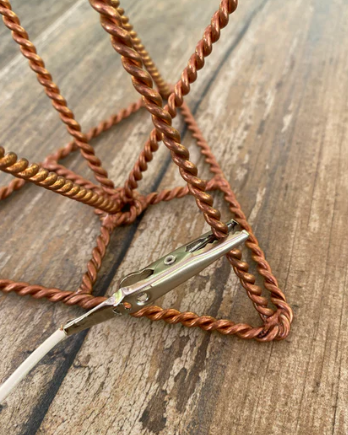 Close-up of a braided brown cord with a metal clip on a wooden surface